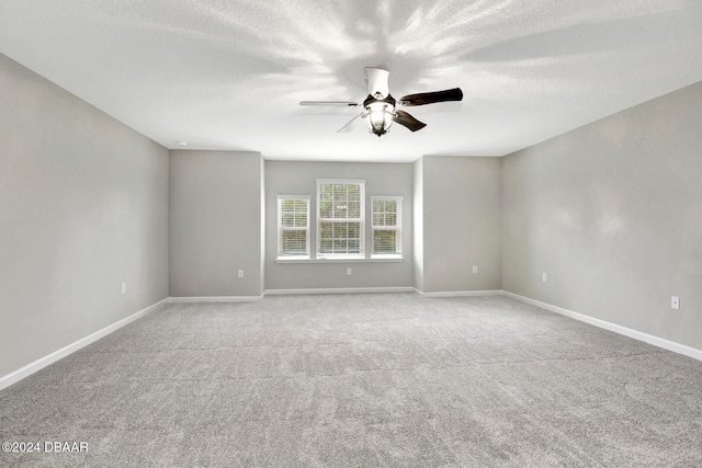 spare room featuring ceiling fan, light colored carpet, and a textured ceiling