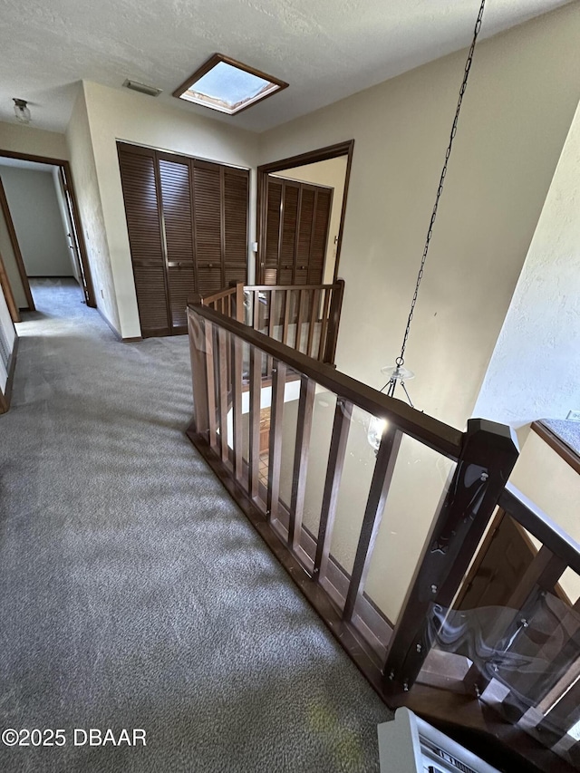 stairway featuring visible vents, carpet floors, and a textured ceiling