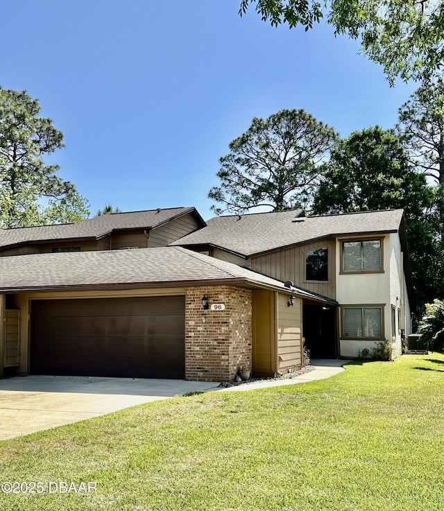 view of front of home featuring roof with shingles, driveway, brick siding, an attached garage, and a front yard