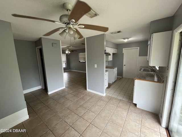 kitchen featuring white cabinets, light tile patterned floors, sink, and a textured ceiling