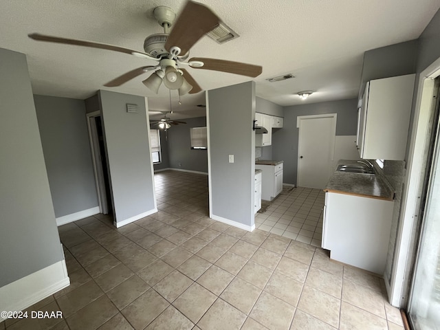 506 Cambridge Cir S, Daytona, FL 32119 - kitchen with ceiling fan, light tile patterned floors, white cabinets, open floor plan, and a textured ceiling