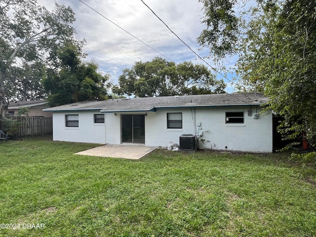 rear view of house with central air condition unit, a patio area, and a lawn