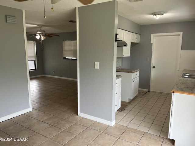 kitchen featuring a textured ceiling, light tile patterned floors, sink, white cabinets, and ceiling fan