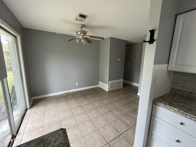 506 Cambridge Cir S, Daytona, FL 32119 - kitchen featuring ceiling fan, light tile patterned flooring, white cabinetry, decorative backsplash, and a textured ceiling