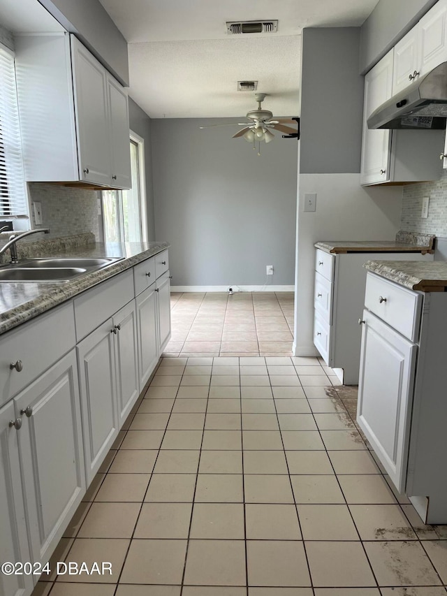 kitchen featuring light tile patterned floors, decorative backsplash, sink, white cabinets, and ceiling fan