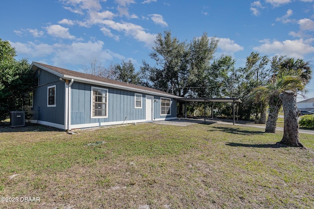 ranch-style house featuring a front lawn, cooling unit, and a carport