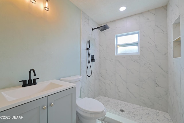 bathroom with vanity, toilet, and tiled shower