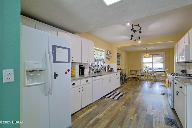 kitchen with dark hardwood / wood-style flooring, white cabinets, pendant lighting, white appliances, and backsplash