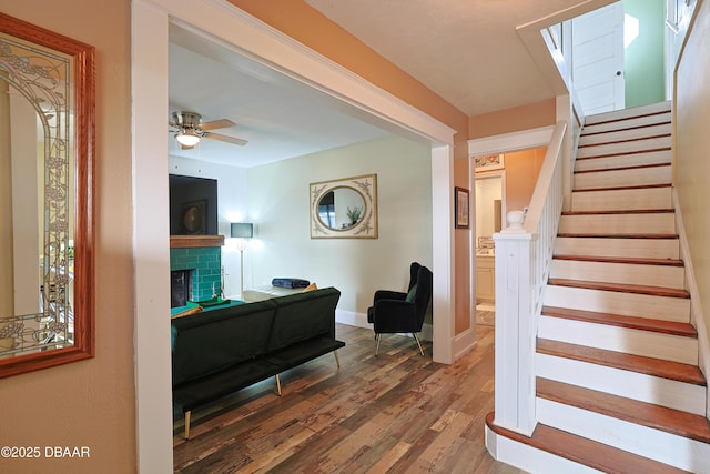 interior space with a brick fireplace, a skylight, wood-type flooring, and ceiling fan