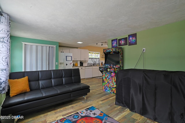 living room with sink, a textured ceiling, and light wood-type flooring