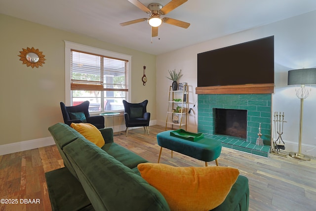 living room featuring a tiled fireplace, hardwood / wood-style flooring, and ceiling fan