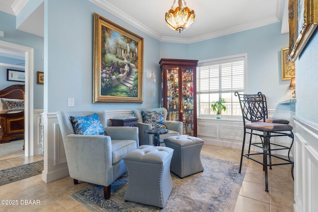 living area featuring a wainscoted wall, ornamental molding, tile patterned flooring, and a notable chandelier