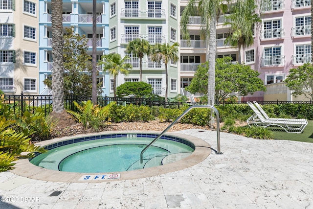 view of swimming pool featuring fence and a hot tub