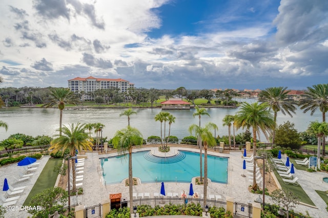 community pool featuring a patio area, a water view, and fence