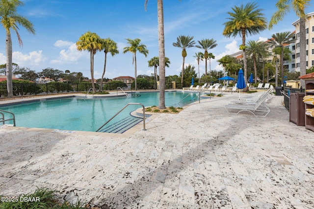 pool with a patio area and fence