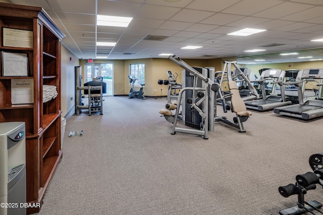 exercise room featuring a paneled ceiling and baseboards