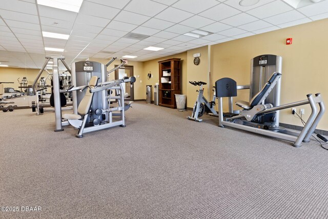 gym featuring baseboards and a drop ceiling