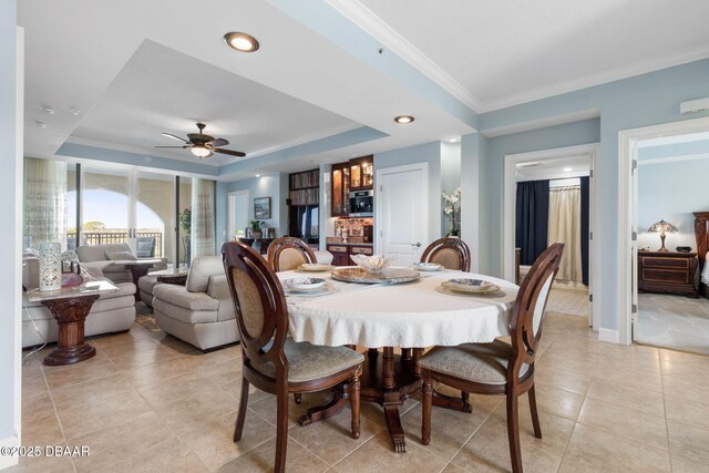 dining area featuring light tile patterned floors, ceiling fan, baseboards, ornamental molding, and a raised ceiling