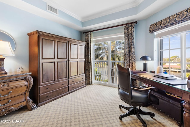 carpeted home office with a tray ceiling, visible vents, and crown molding