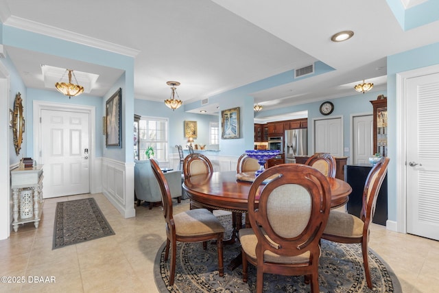 tiled dining room featuring a raised ceiling and ornamental molding