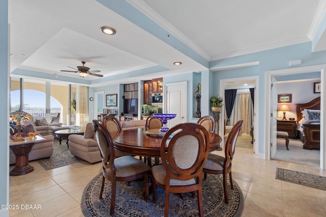 tiled dining space featuring a tray ceiling, ceiling fan, and ornamental molding