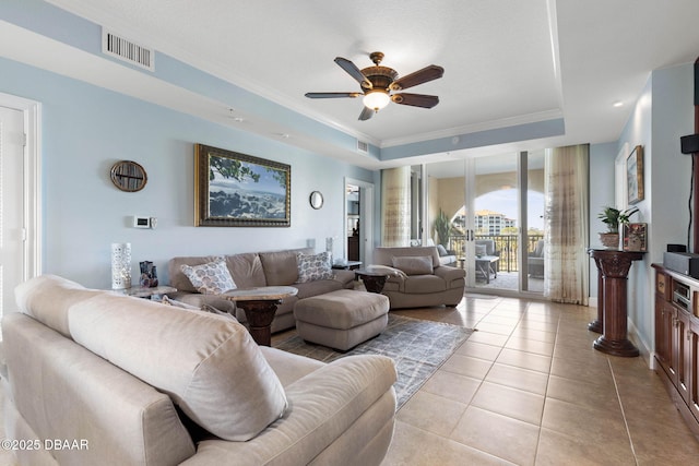 living room featuring light tile patterned flooring, a ceiling fan, french doors, ornamental molding, and a raised ceiling