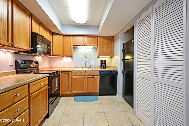 kitchen with light stone counters, black appliances, a textured ceiling, sink, and light tile patterned floors