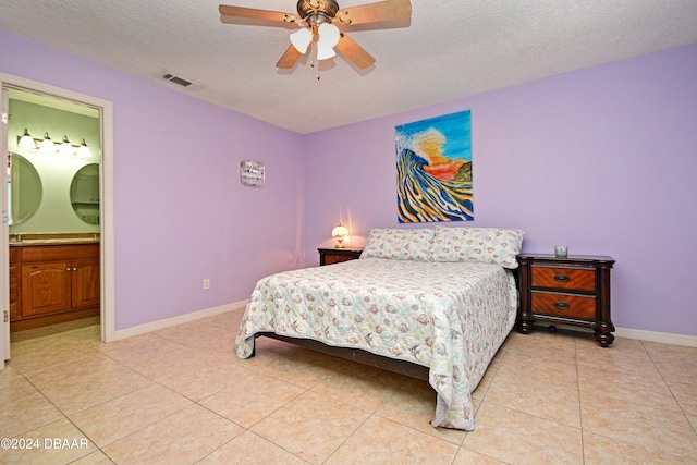 bedroom featuring light tile patterned flooring, ceiling fan, connected bathroom, and a textured ceiling