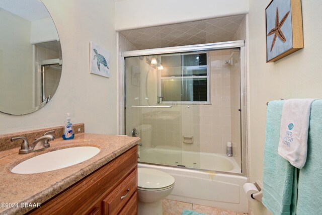 full bathroom featuring vanity, combined bath / shower with glass door, and toilet