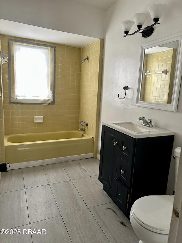 full bathroom featuring vanity, tiled shower / bath combo, and toilet