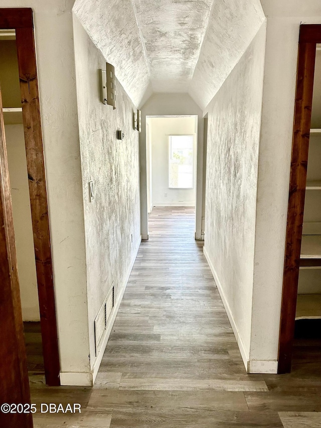 corridor with lofted ceiling and light hardwood / wood-style floors