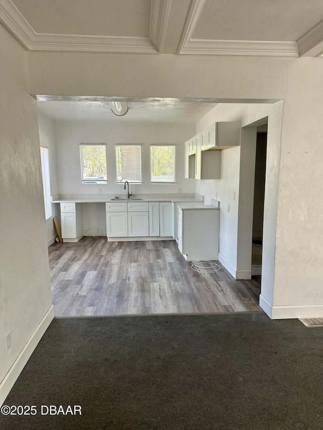 kitchen with sink, crown molding, white cabinetry, built in desk, and light hardwood / wood-style floors