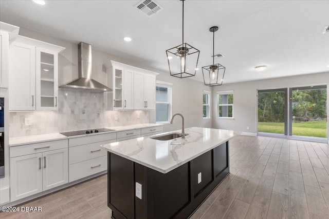 kitchen with white cabinets, wall chimney exhaust hood, light hardwood / wood-style floors, and sink