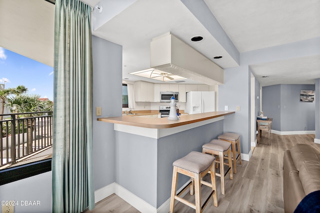 kitchen featuring kitchen peninsula, appliances with stainless steel finishes, a kitchen bar, and plenty of natural light