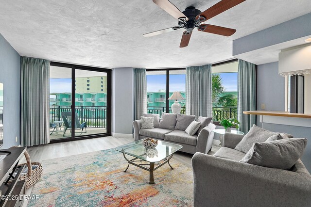 living area with wood finished floors, expansive windows, and ceiling fan