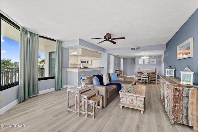 living room with ceiling fan with notable chandelier and light wood-type flooring