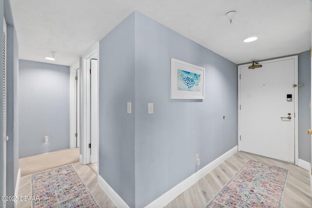 hallway with light wood-type flooring and baseboards