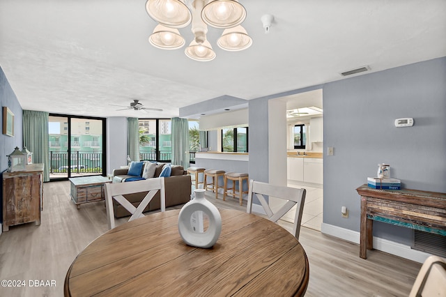 dining space with light hardwood / wood-style flooring, ceiling fan, floor to ceiling windows, and sink