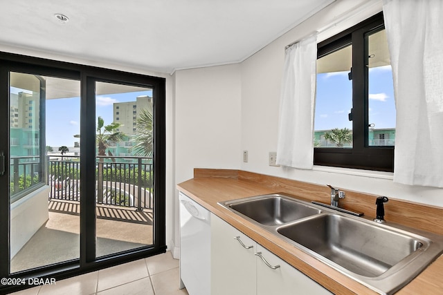 kitchen with white cabinets, light tile patterned floors, dishwasher, and sink