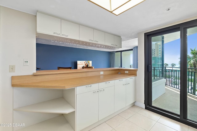 kitchen featuring open shelves, plenty of natural light, light tile patterned flooring, and white cabinets