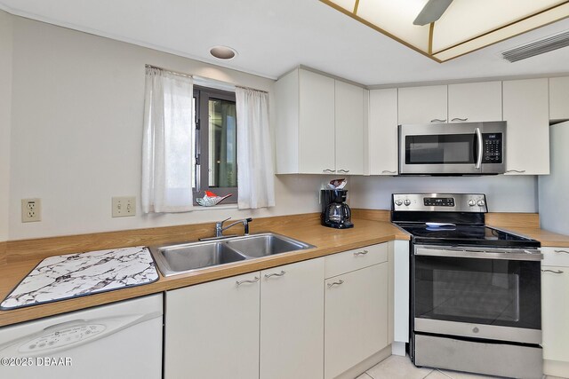 kitchen featuring stainless steel appliances, a sink, light countertops, and white cabinetry