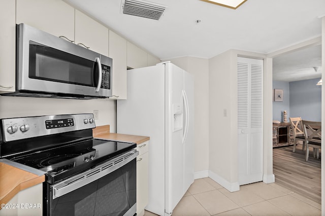 kitchen with white cabinets, appliances with stainless steel finishes, and light tile patterned floors