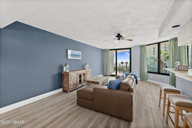 living room featuring expansive windows, ceiling fan, and light hardwood / wood-style flooring