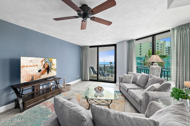 living area featuring baseboards, wood finished floors, a ceiling fan, and a textured ceiling