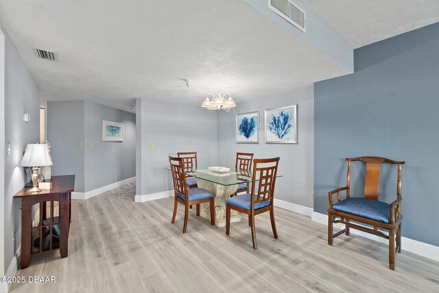 dining space featuring light wood-style floors, a chandelier, and baseboards