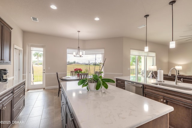 kitchen with dark brown cabinetry, a kitchen island, sink, light stone counters, and stainless steel dishwasher