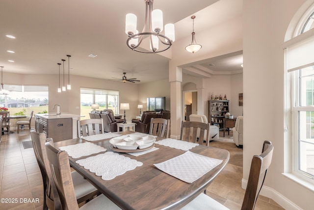 dining space featuring ceiling fan with notable chandelier, sink, and light tile patterned floors