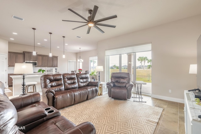 living room featuring ceiling fan with notable chandelier and light tile patterned floors