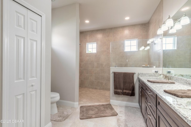 bathroom with tiled shower, vanity, toilet, and tile patterned flooring