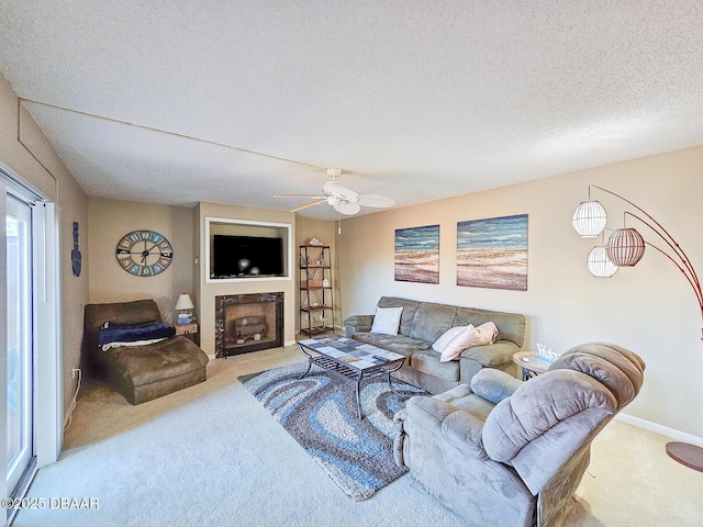 living area with baseboards, a ceiling fan, a fireplace with flush hearth, a textured ceiling, and carpet floors